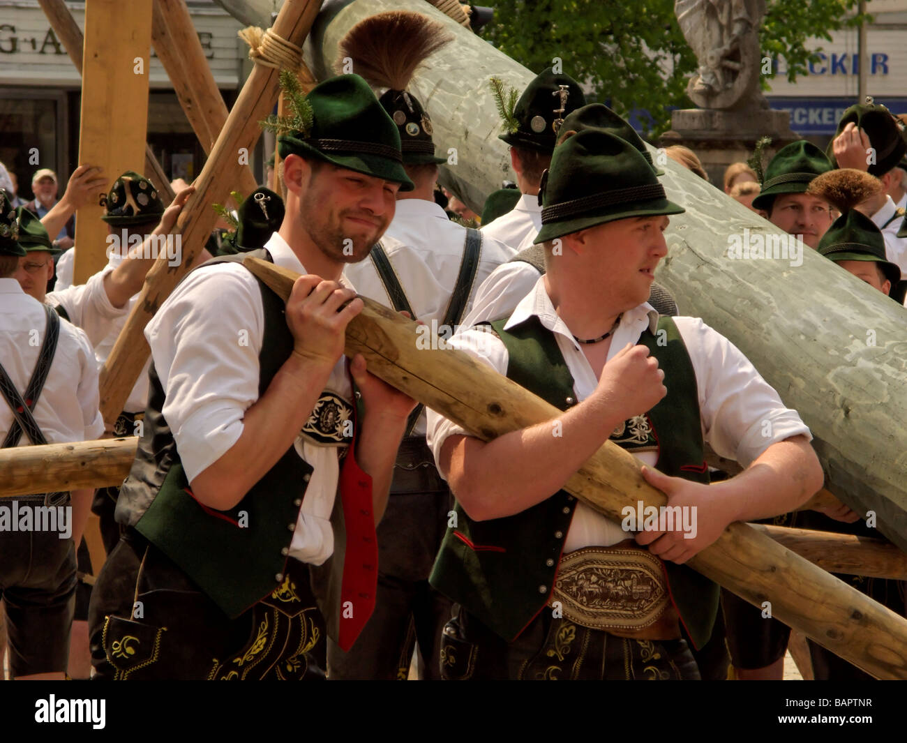 Bavaresi in abito tradizionale sollevando il Maypole Foto Stock