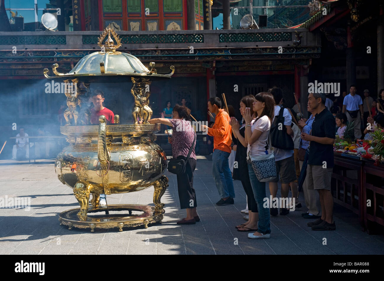 Buddisti e taoisti adoratori bruciare bastoncini di incenso come offerta rituale a Mengjia Tempio Lungshan. Taipei, Taiwan. Foto Stock