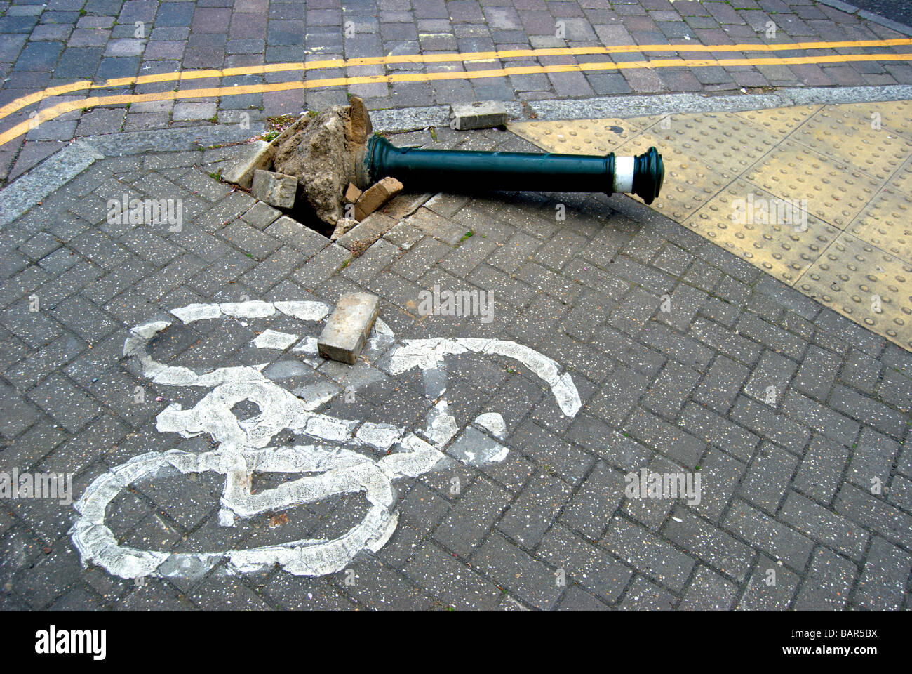 Il traffico britannico bollard su un terreno che è stato colpito dal veicolo con pavimentazione danneggiata e adiacente al percorso del ciclo di marcatura Foto Stock