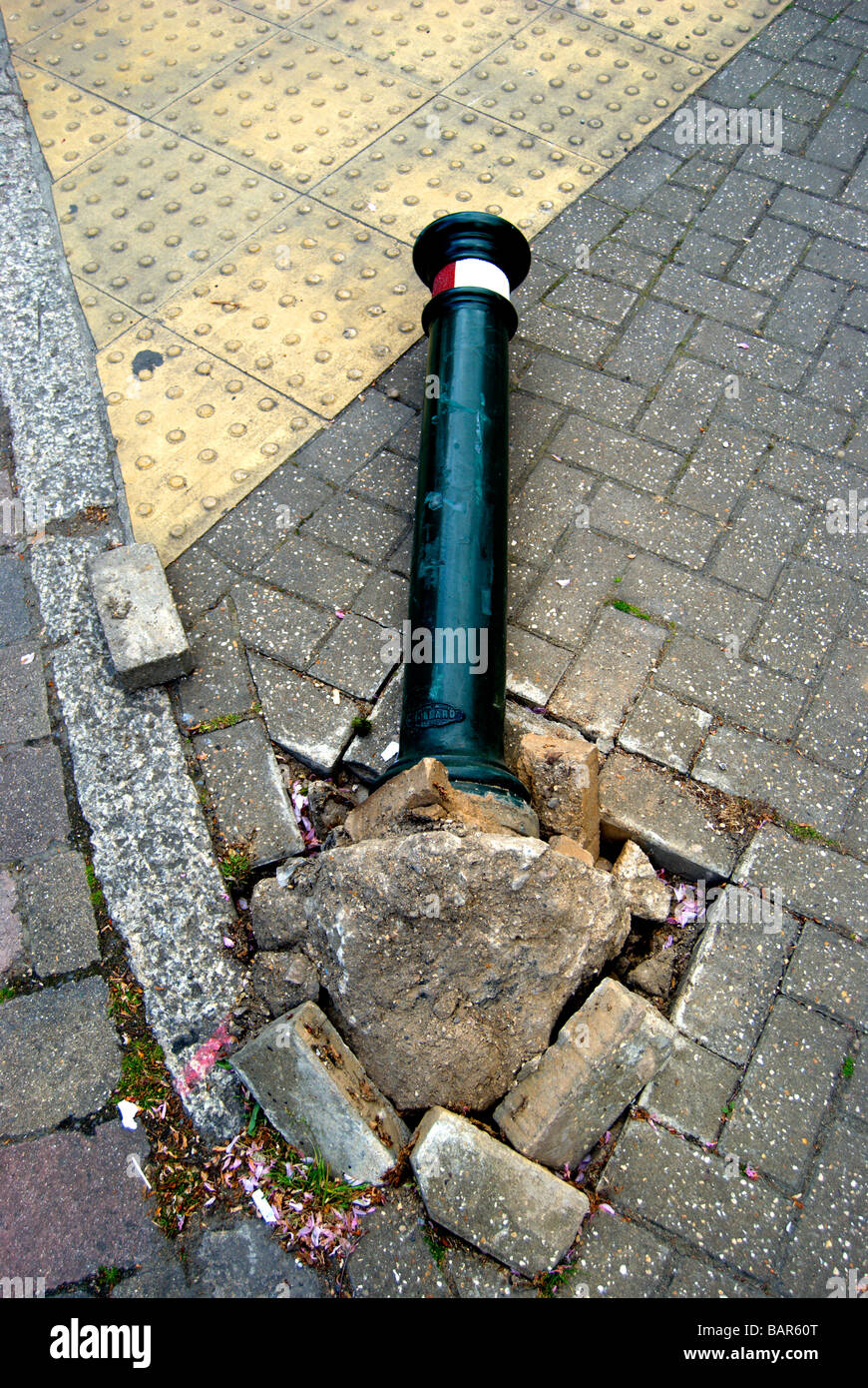 Il traffico britannico bollard su un terreno che è stato colpito dal veicolo con danni al marciapiede Foto Stock