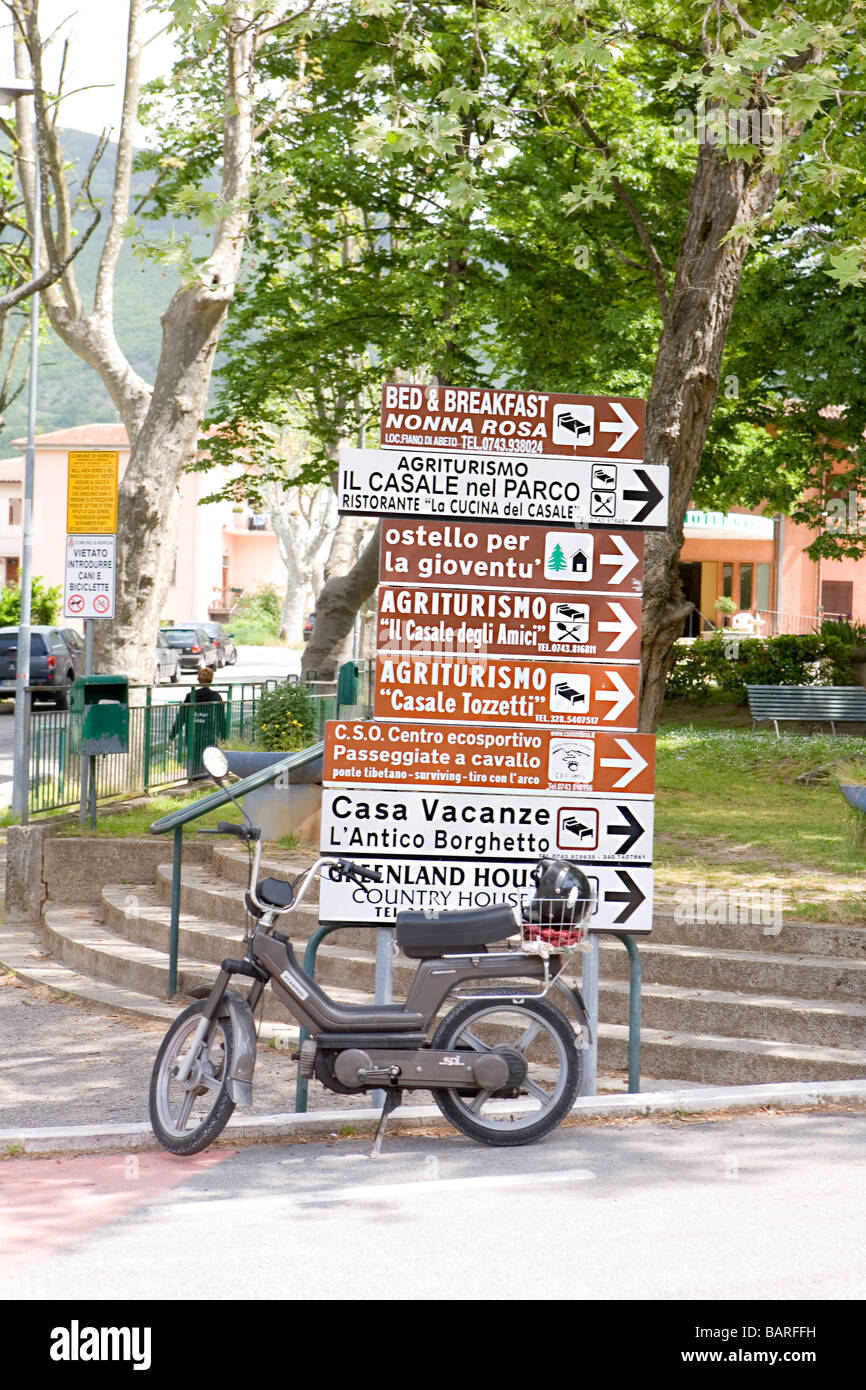 Scooter prima di un elenco di indicazioni turistiche nell'antica città di Norcia in Umbria in Itlay Foto Stock