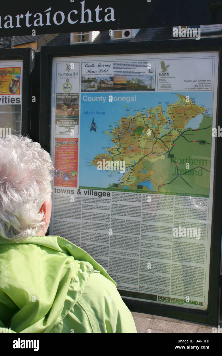Donna lettura tourist information board e la mappa della Contea di Donegal a Donegal Town, Irlanda Foto Stock