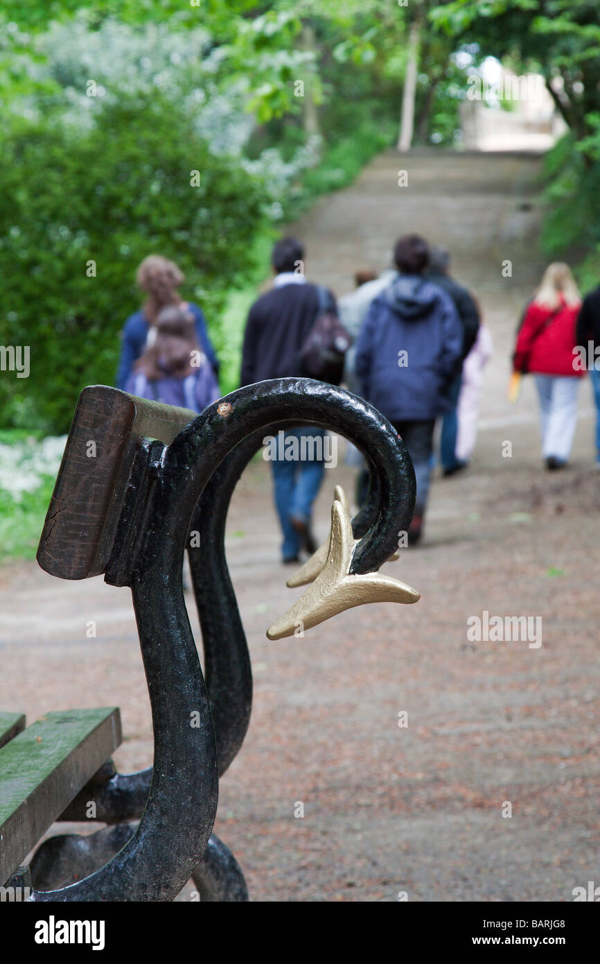 Un gruppo di giovani a piedi lungo un percorso lontano da una panchina nel parco Foto Stock