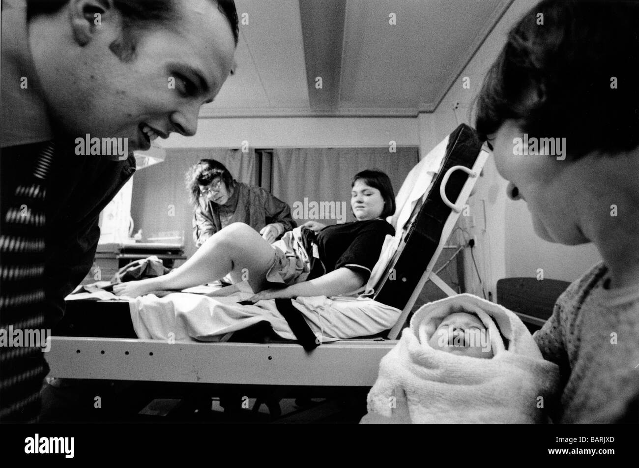 Il padre e la nonna ammirare baby Erin Megan mentre la levatrice assiste a Jenny, la madre a Homerton Hospital di Londra. Foto Stock