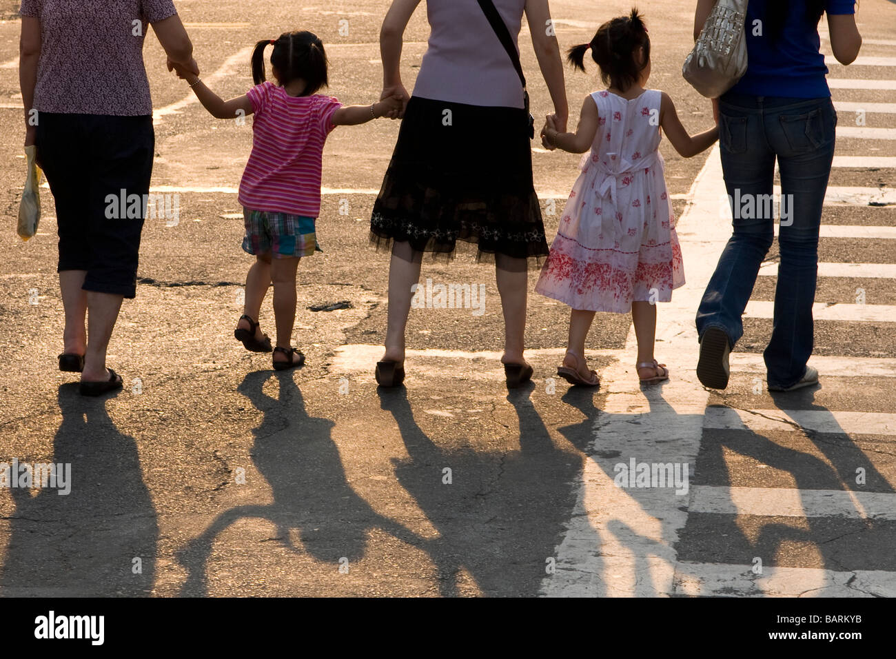 I bambini e gli adulti si stringono la mano durante l'attraversamento di una strada nella città di New York. Foto Stock