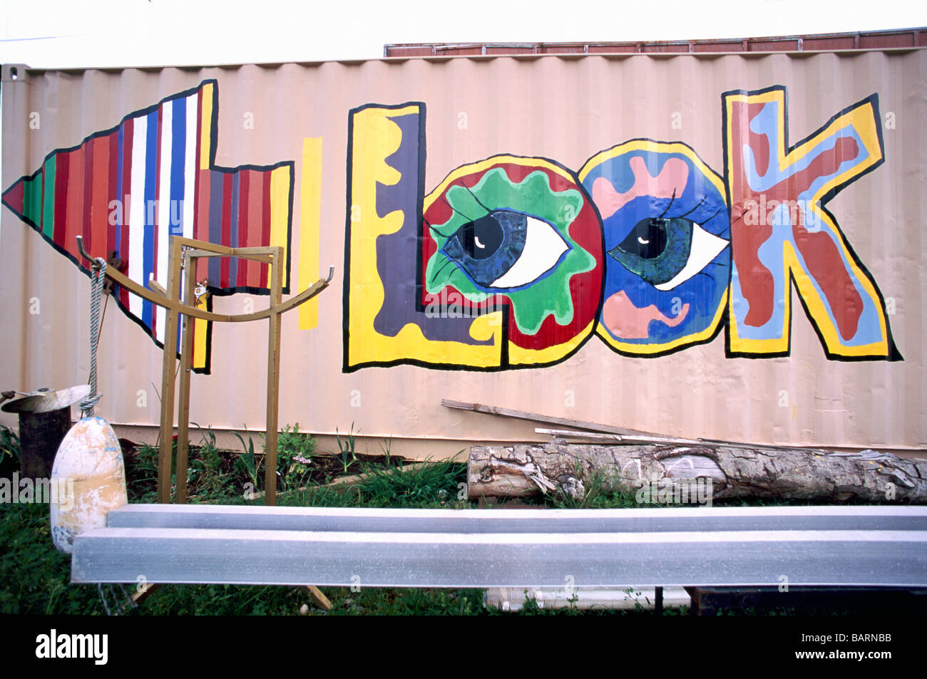 Look colorati graffiti arte segno di informazioni con freccia rivolta in direzione verso sinistra dipinta sul lato esterno la parete di un edificio Foto Stock
