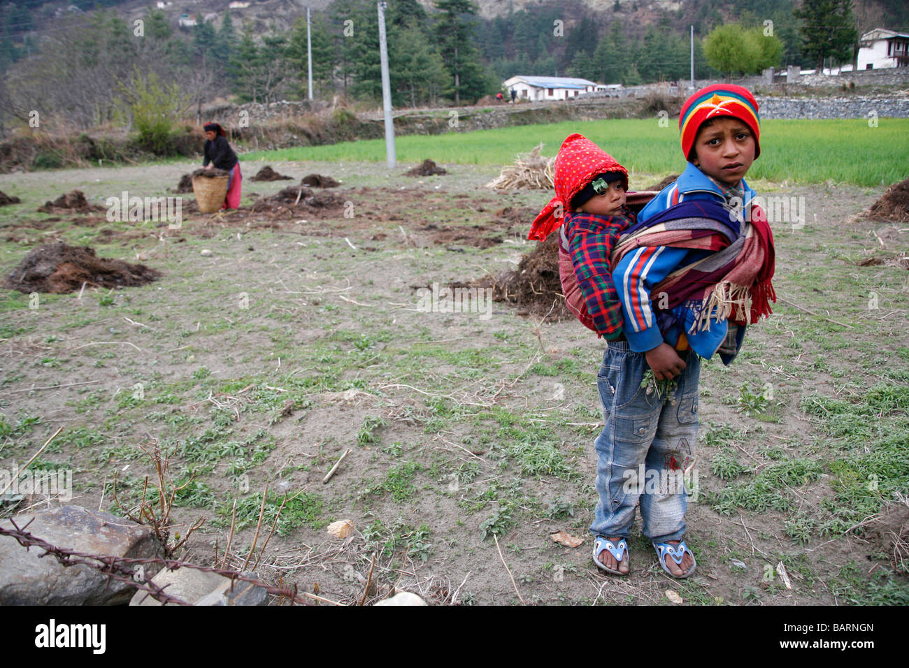 Annapurnas Nepal 30 marzo 2008 Giovane ragazzo prendersi cura di suo fratello più piccolo mentre la madre è in modalità di lavoro nel campo Foto Stock