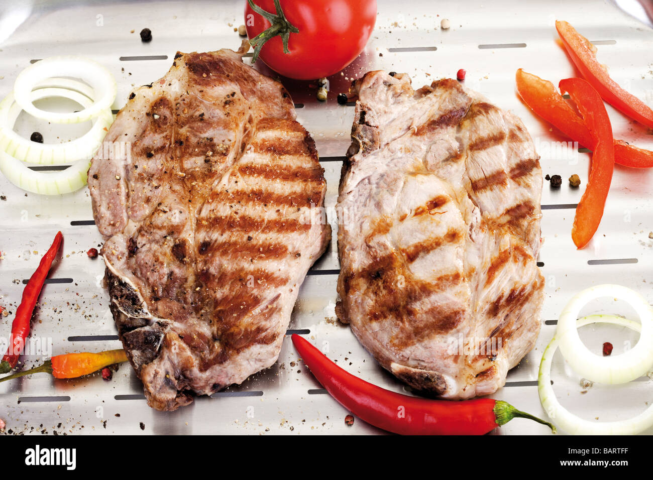 Braciole di maiale alla griglia sulla griglia in alluminio pan Foto Stock
