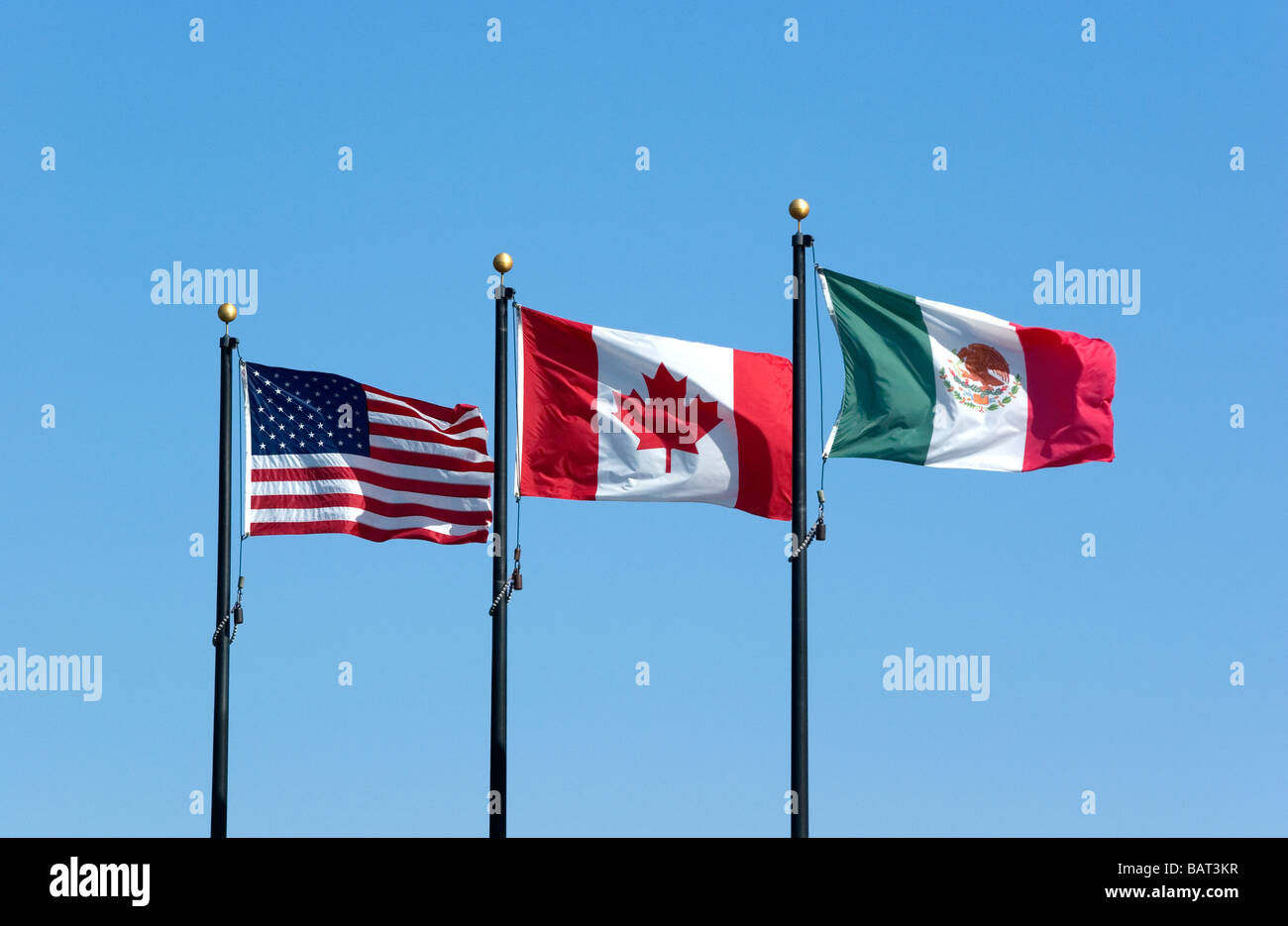 Il NAFTA, americani e canadesi bandierine messicane battenti contro il cielo blu Foto Stock