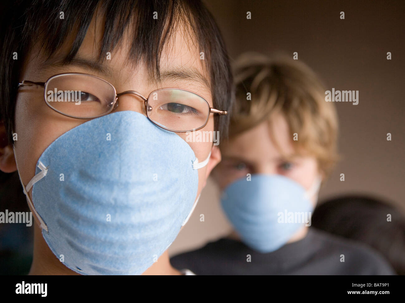 Primo piano dei due figli di età 12 e 10 di indossare le maschere Foto Stock