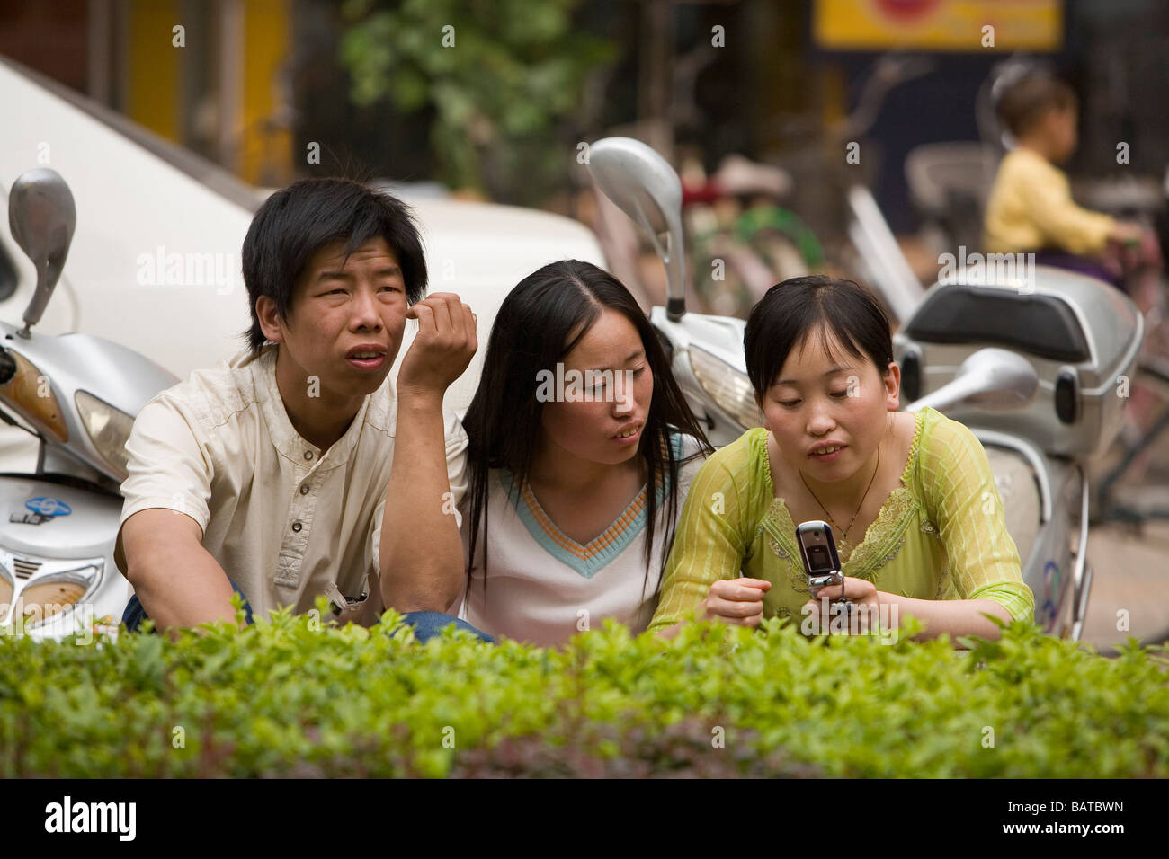 LISHI, CINA - GIUGNO 2006: Una giovane donna guarda un messaggio sul suo cellulare con due amici. Lishi si trova nella provincia dello Shanxi, una delle province più inquinate della Cina. Foto Stock