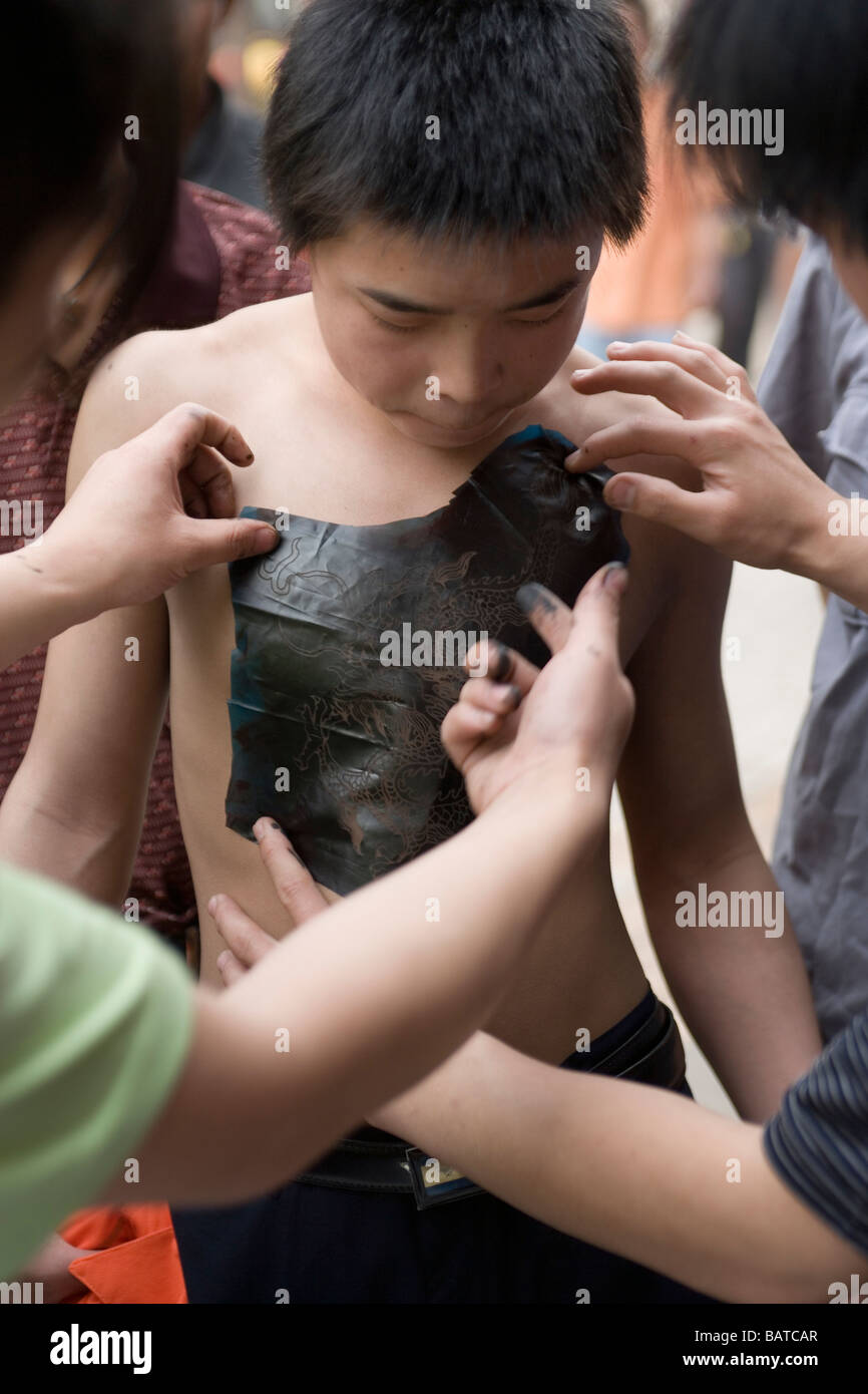 Un ragazzo adolescente ha l immagine di un drago stampata sul petto con inchiostro della stampante Foto Stock