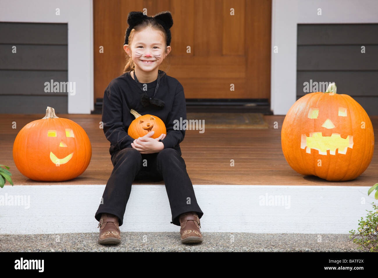 Razza mista giovane ragazza in costume gatto azienda zucca di Halloween Foto Stock