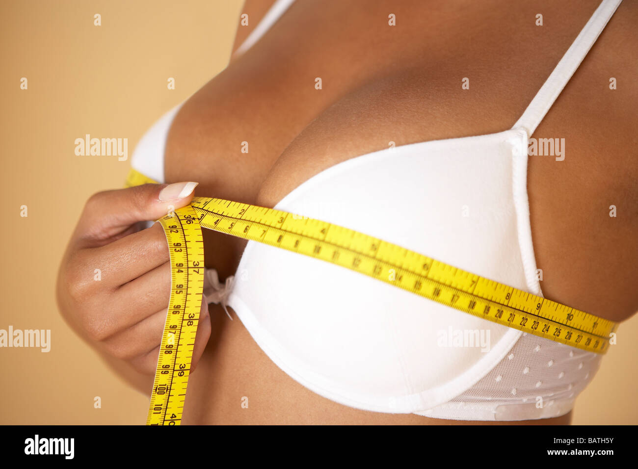 Dimensione del seno. Donna misurando la sua dimensione del seno (busto dimensioni) con un nastro di misurazione. Foto Stock