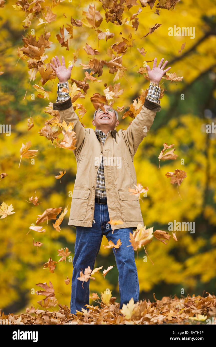 Uomo ispanico gettando le foglie di autunno Foto Stock