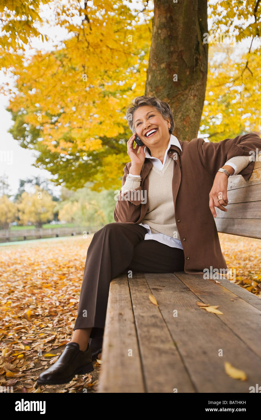 Donna africana parlando al cellulare su una panchina nel parco in autunno Foto Stock