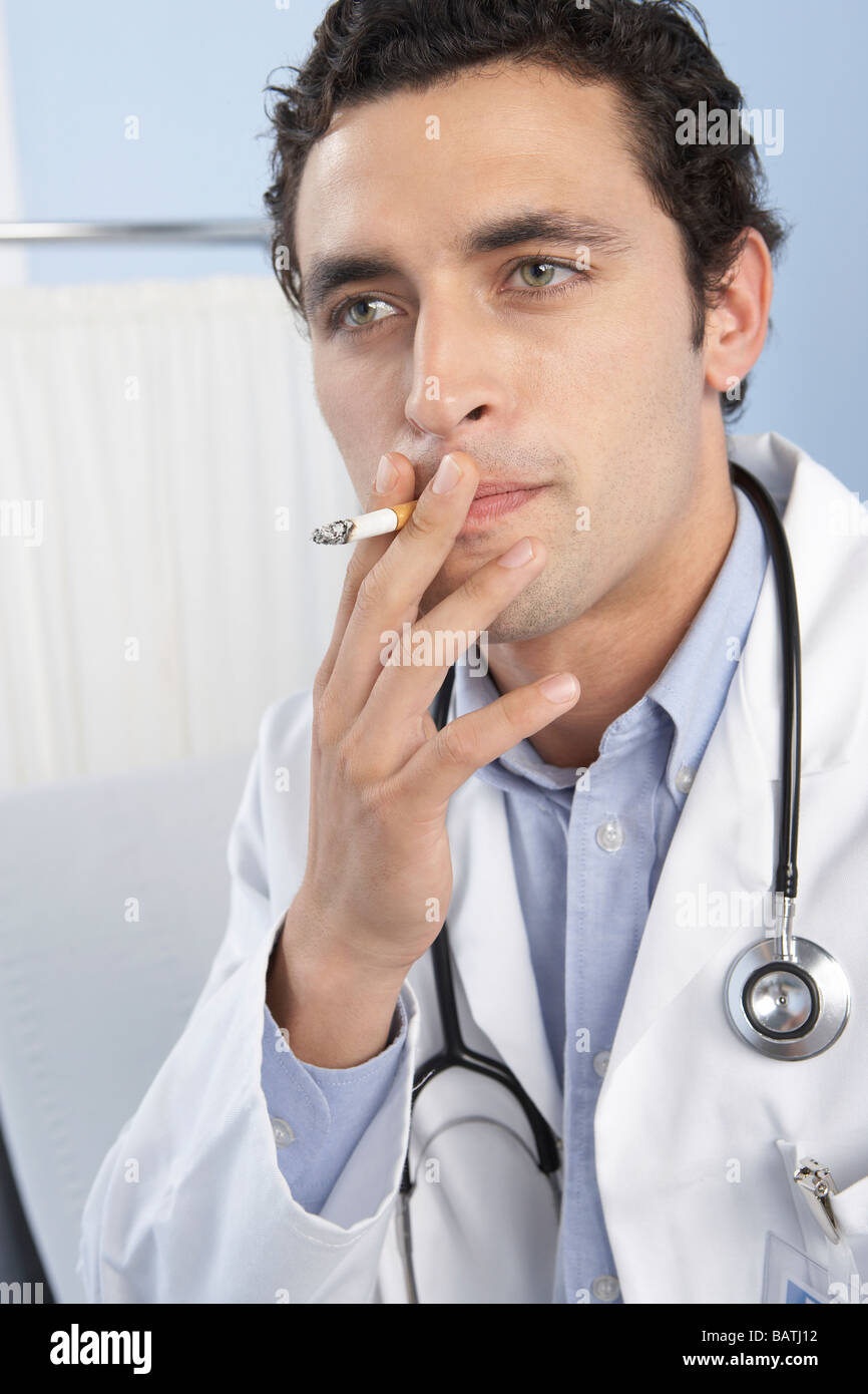 Medico di fumare una sigaretta. Le sigarette contengono il farmaco dipendenza da nicotina e che causano il cancro sostanze Foto Stock