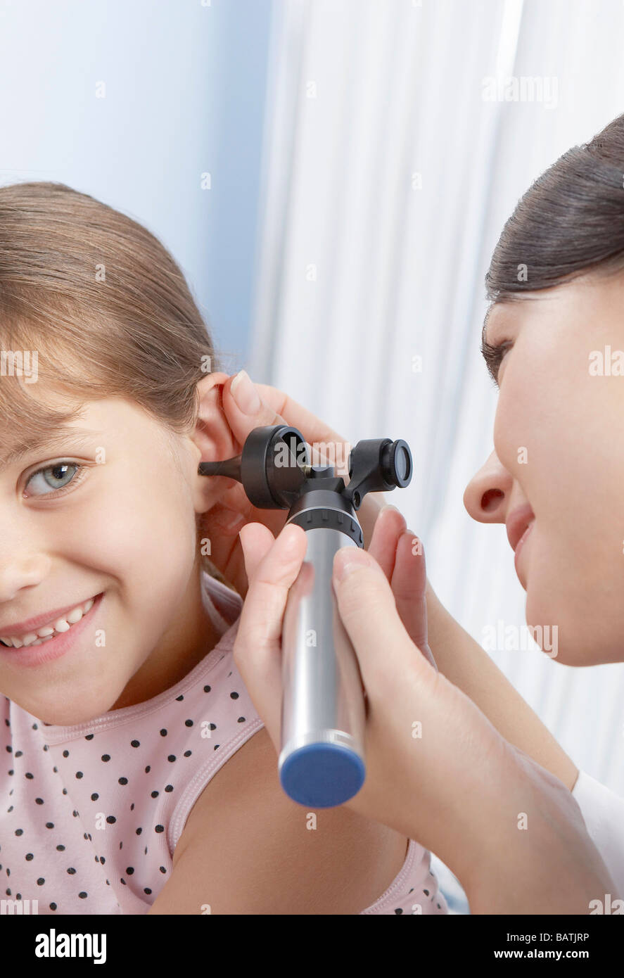 Esame dell'orecchio. Otoscopio essendo utilizzato da una pratica generale medico per esaminare un sei-anno-vecchia ragazza l orecchio. Foto Stock