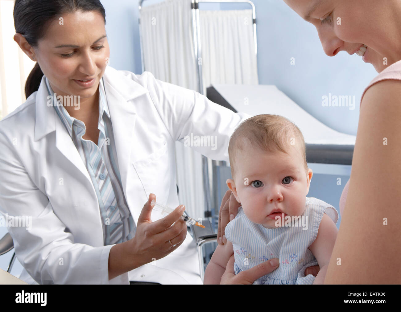 La vaccinazione. 5-mese-vecchio bambina avente un vaccino iniettato nel suo braccio da una siringa. Foto Stock