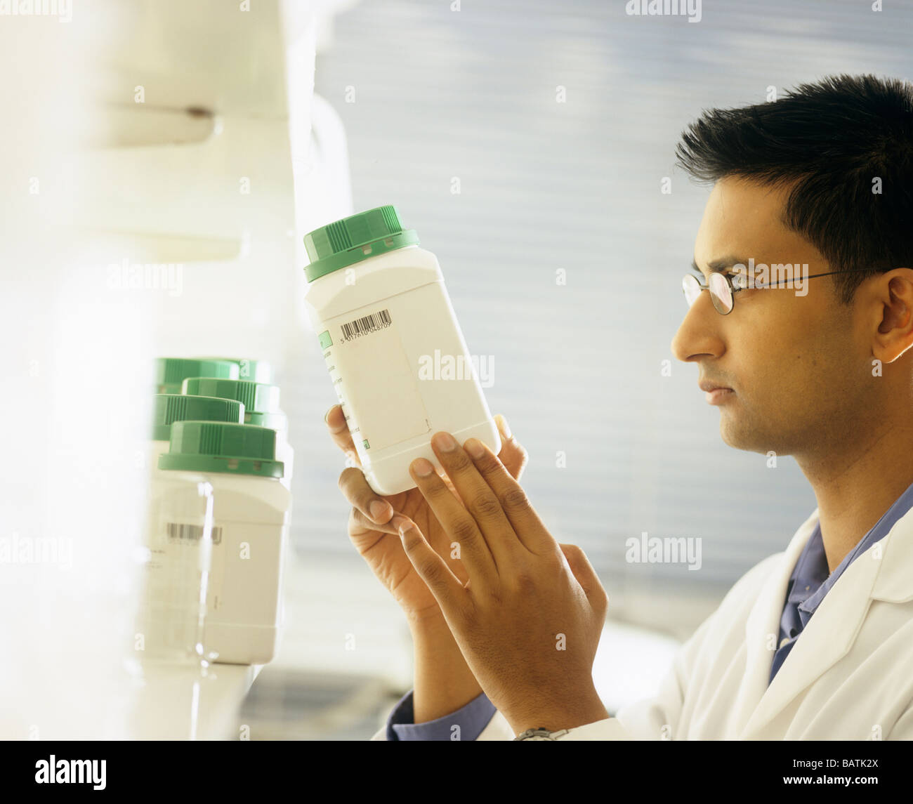 Ricercatore in un laboratorio di lettura dell'etichetta su una bottiglia. Foto Stock