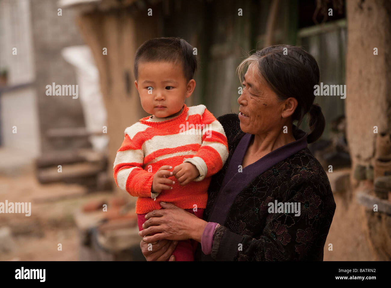 Changchun, provincia di Jilin ,la Cina. Un giovane ragazzo tra le braccia della madre al di fuori della loro casa. Foto Stock