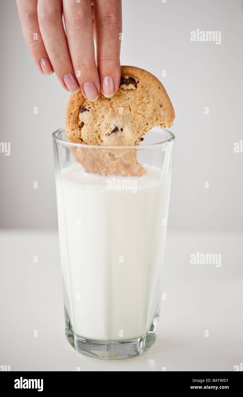 Donna di mano cookie di immersione nel bicchiere di latte Foto Stock