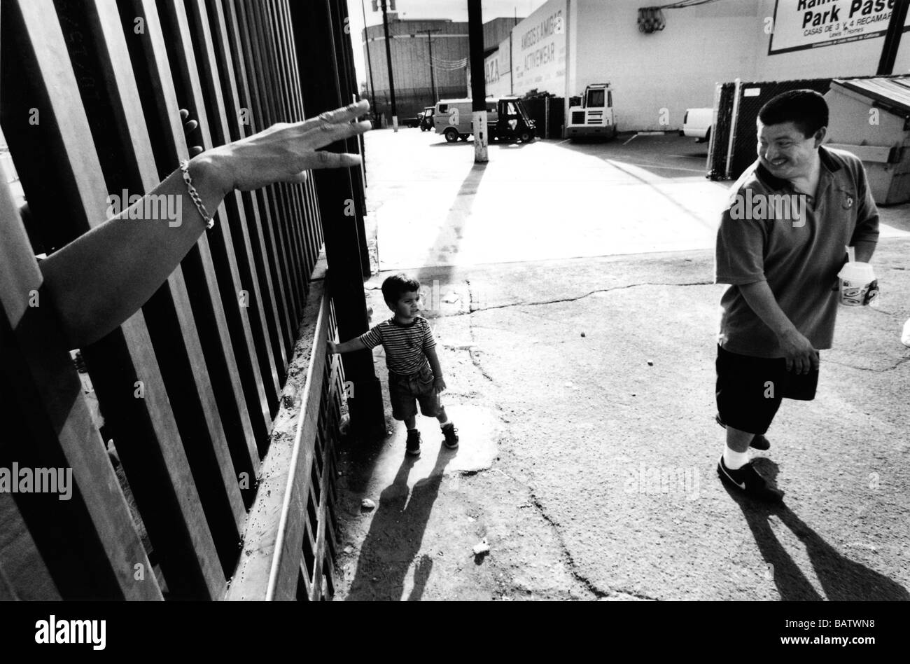 Noi frontiera messico Calexico usa una donna sul lato messicano onde ai suoi parenti attraverso la recinzione di confine dalla stazione degli autobus. Foto Stock