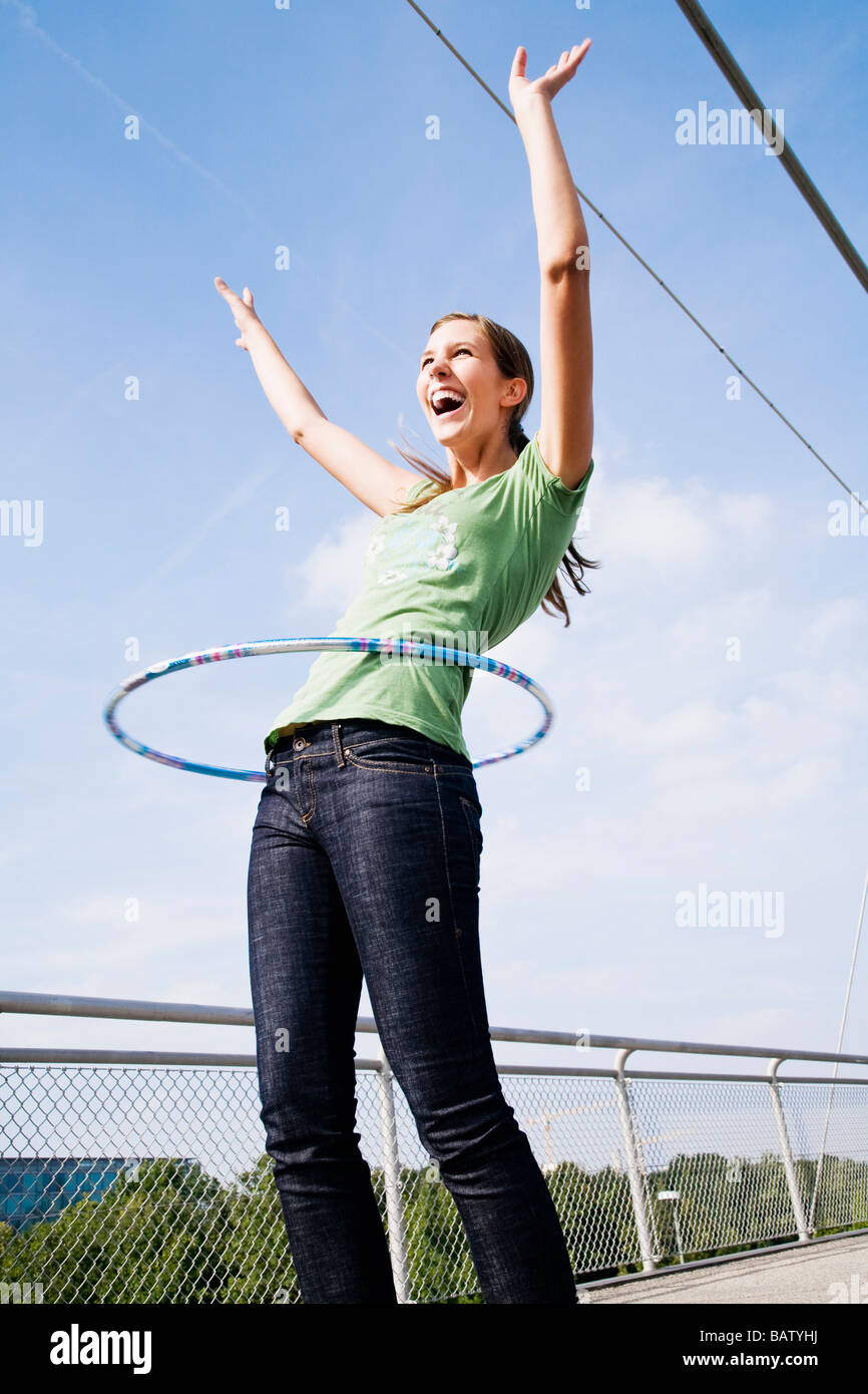 Giovane donna facendo hula hoop sul ponte Foto Stock