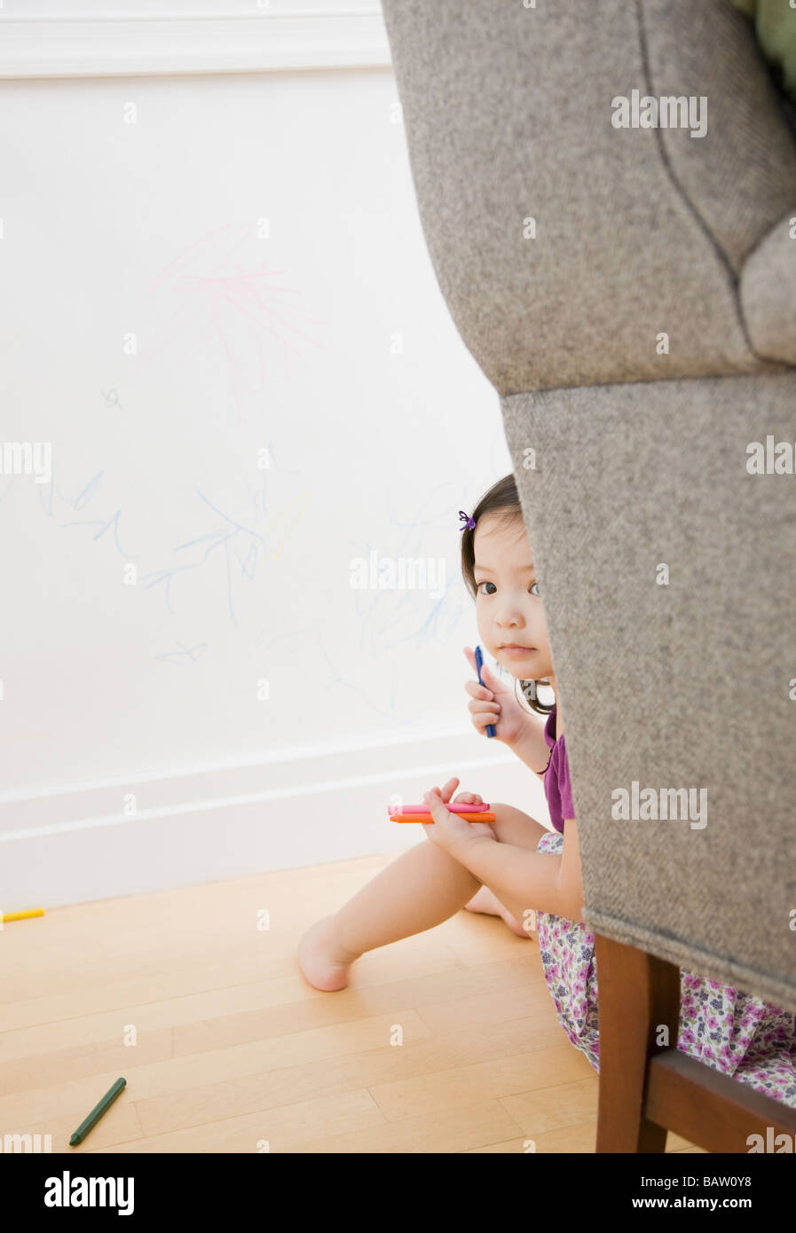 Bambino bambina che si nasconde dietro la sedia Foto Stock