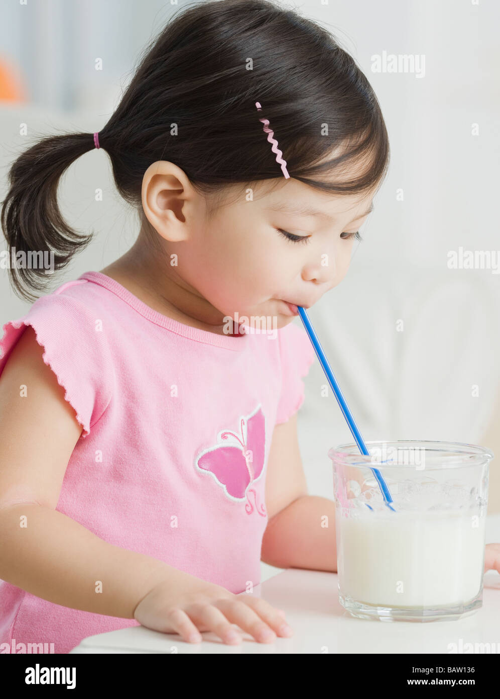 Razza mista ragazza bere latte con paglia Foto Stock