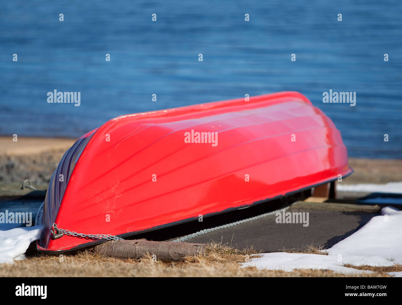 Rowboat rosso in vetroresina / skiff / dinghy ribaltato in inverno Foto Stock