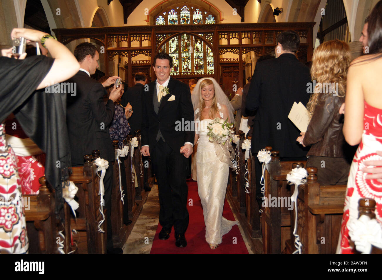Giovane coppia di sposi novelli a piedi giù per la navata della chiesa North Yorkshire. Modello Regno Unito rilasciato Foto Stock