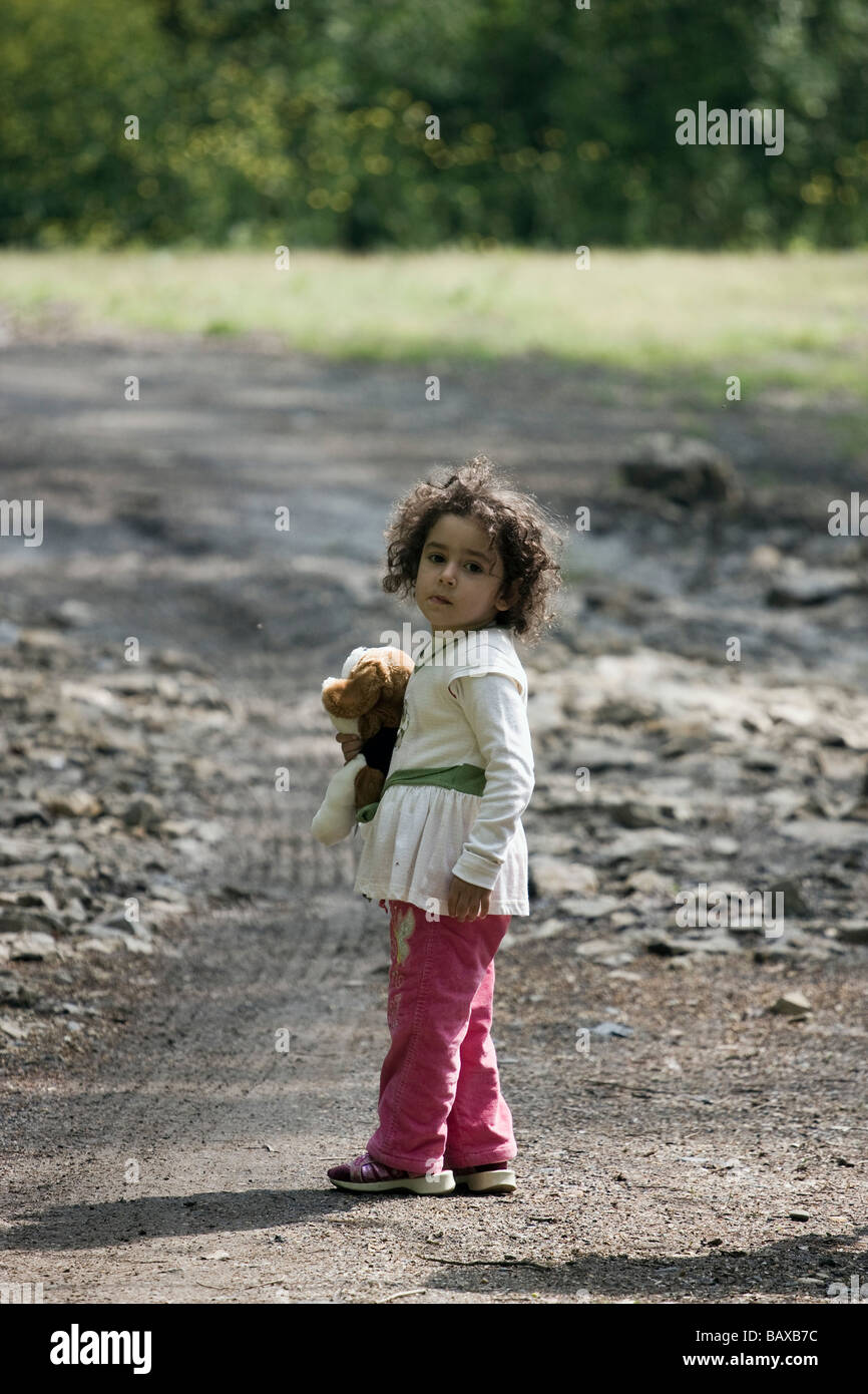 Un capretto ragazza è in possesso di un giocattolo un guardare indietro a metà Foto Stock