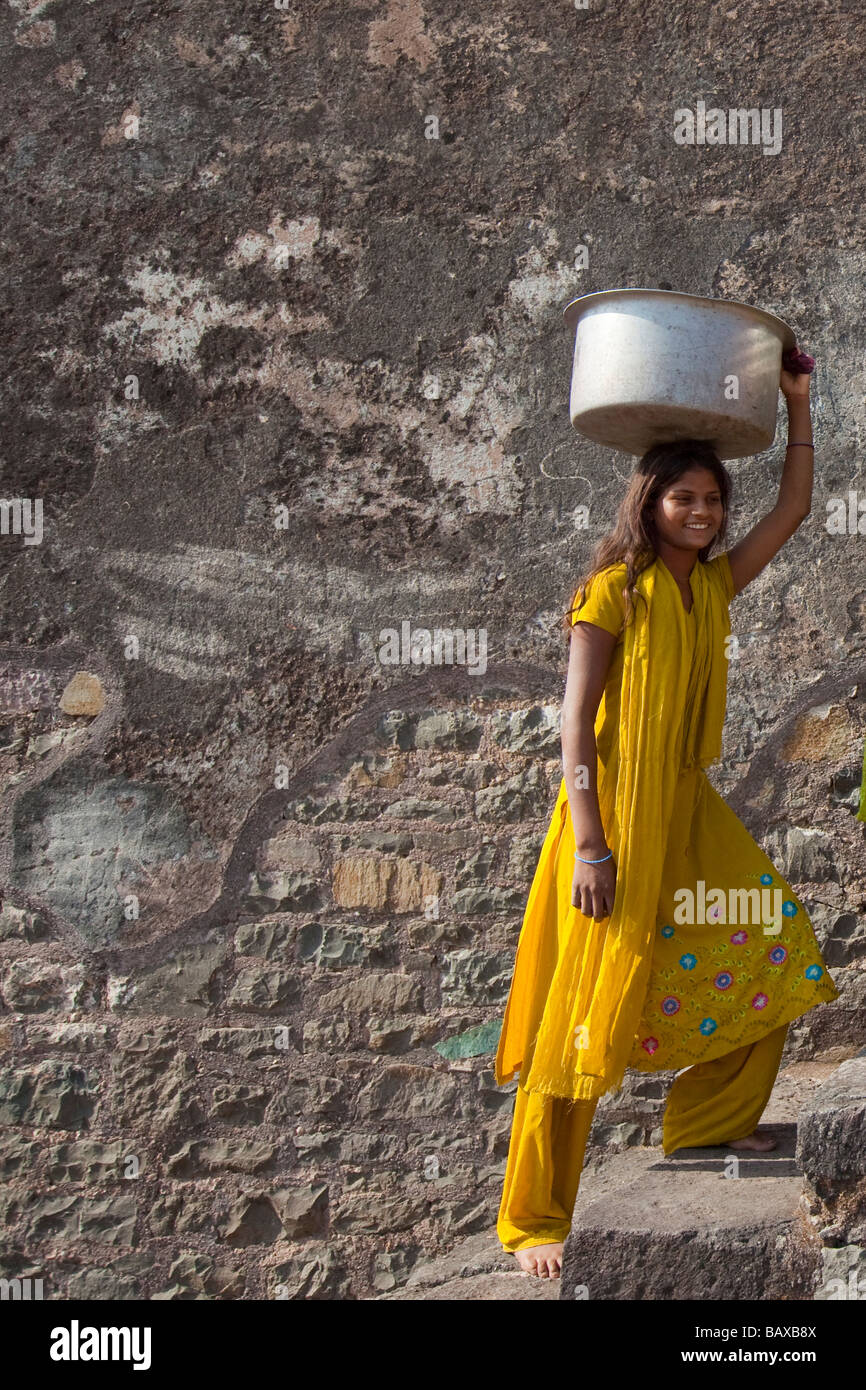 La ragazza che porta il carico sul suo capo nella Royal Enclosure Mandu in India Foto Stock