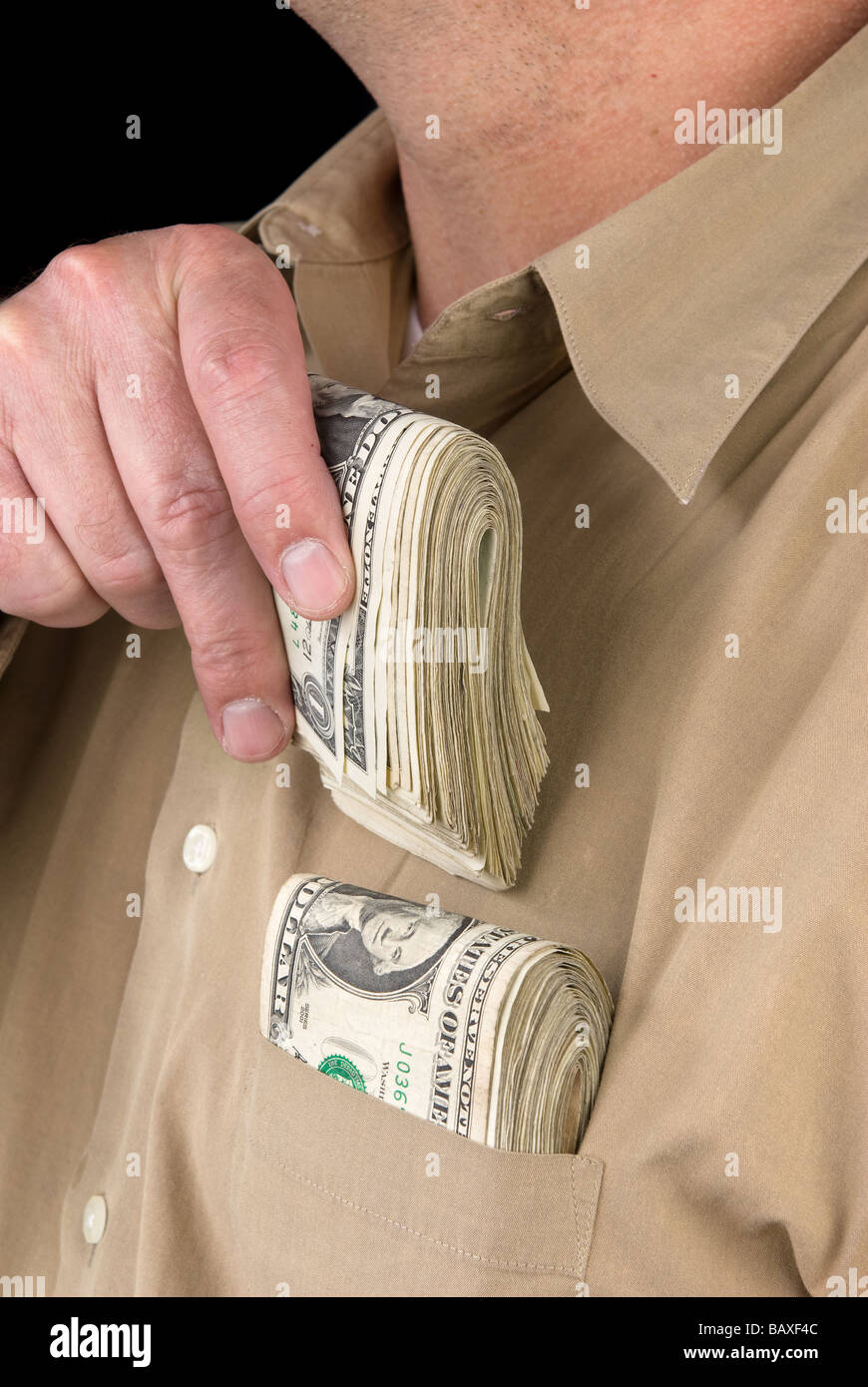 Un uomo luoghi mazzette di denaro contante nella sua tasca della camicia Foto Stock