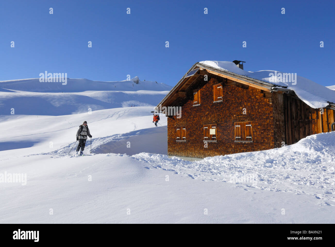 Gli sciatori che arrivano al coperto di neve e rifugio alpino, Schwarzwassertal, Kleinwalsertal, Allgaeu gamma, Allgaeu, Vorarlberg, Austria Foto Stock