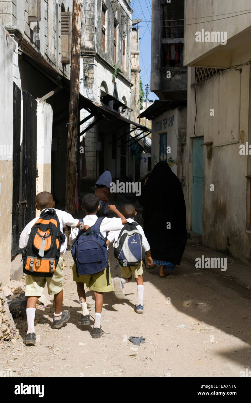 Tre ragazzi della scuola a piedi attraverso lane nella Città Vecchia, Mombasa, in Kenya Foto Stock