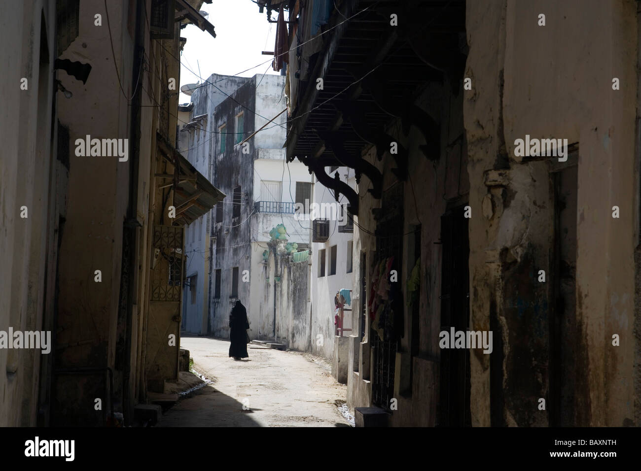 Donna musulmana a piedi attraverso lane nella Città Vecchia, Mombasa, in Kenya Foto Stock