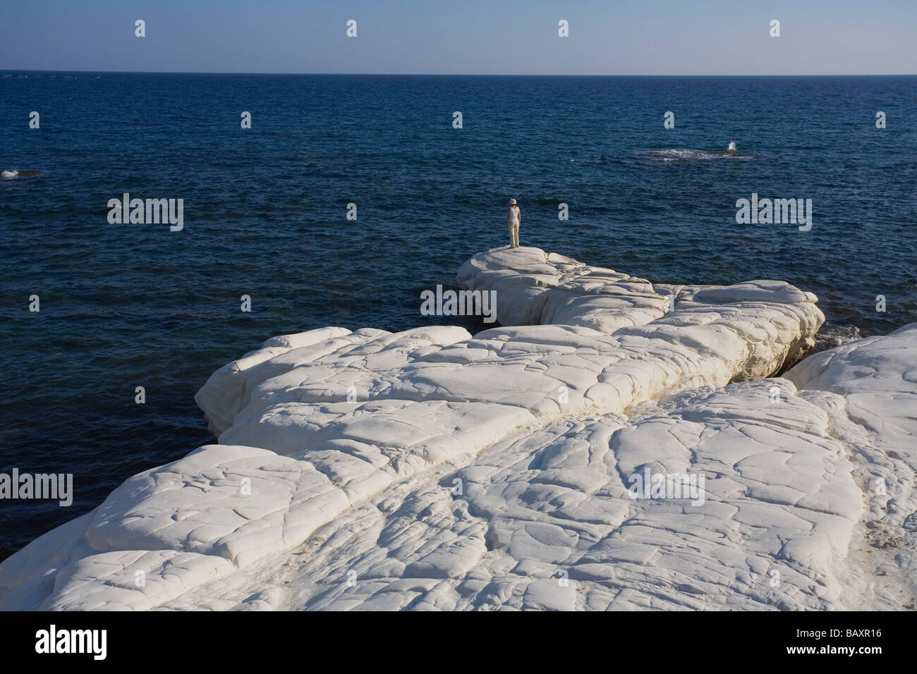 Una donna in piedi sulle rocce che guarda al mare, rocce bianche lungo la costa a governatori Beach, vicino a Limassol, vicino a Limassol, Sud Foto Stock
