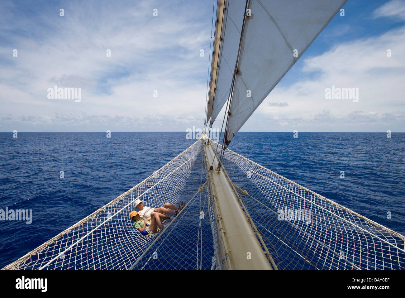 Giovane rilassante in bompresso net della vela Cruiseship Star Flyer (Star Clippers Crociere), Bora Bora, Isole della Società, Francese Pol Foto Stock