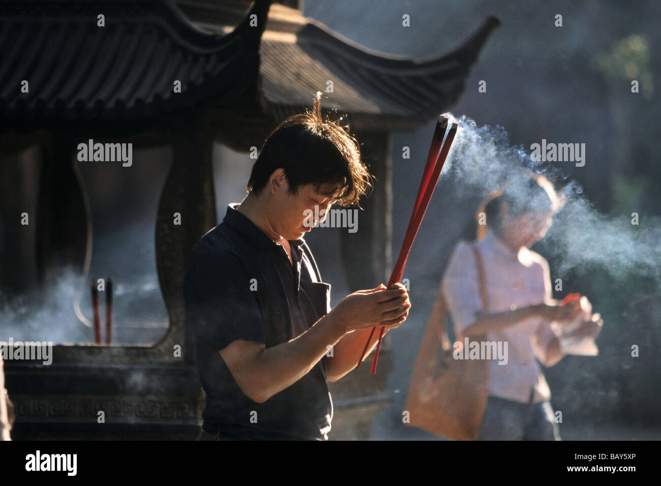 Uomo che prega con bastoncini di incenso, Puji Si tempio buddista, Isola di Putuo Shan vicino a Shanghai, nella provincia di Zhejiang, il Mar della Cina orientale, Foto Stock