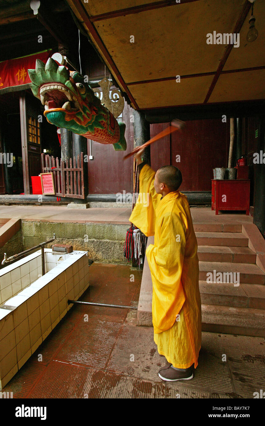 Monaco battendo su pesci di legno, chiamata alla preghiera, Xixiang Chi monastero, Emei Shan, nella provincia di Sichuan, in Cina, Asia Foto Stock