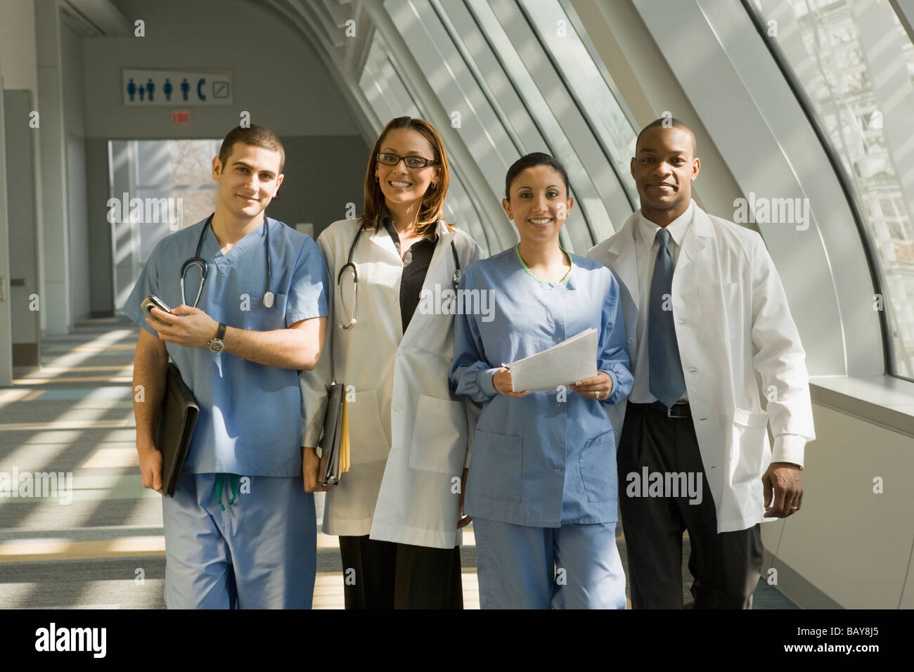 Multi-etnico medici e infermieri che pongono in corridoio Foto Stock