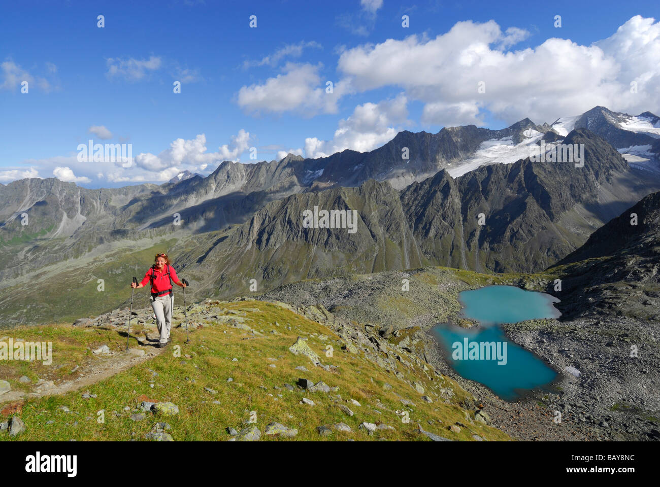 Giovane donna escursionismo, salita a Rinnenspitze, vista lago e Rinnensee Ruderhofspitze, Stubaier Alpen gamma, Stubai, Tirolo, Aust Foto Stock