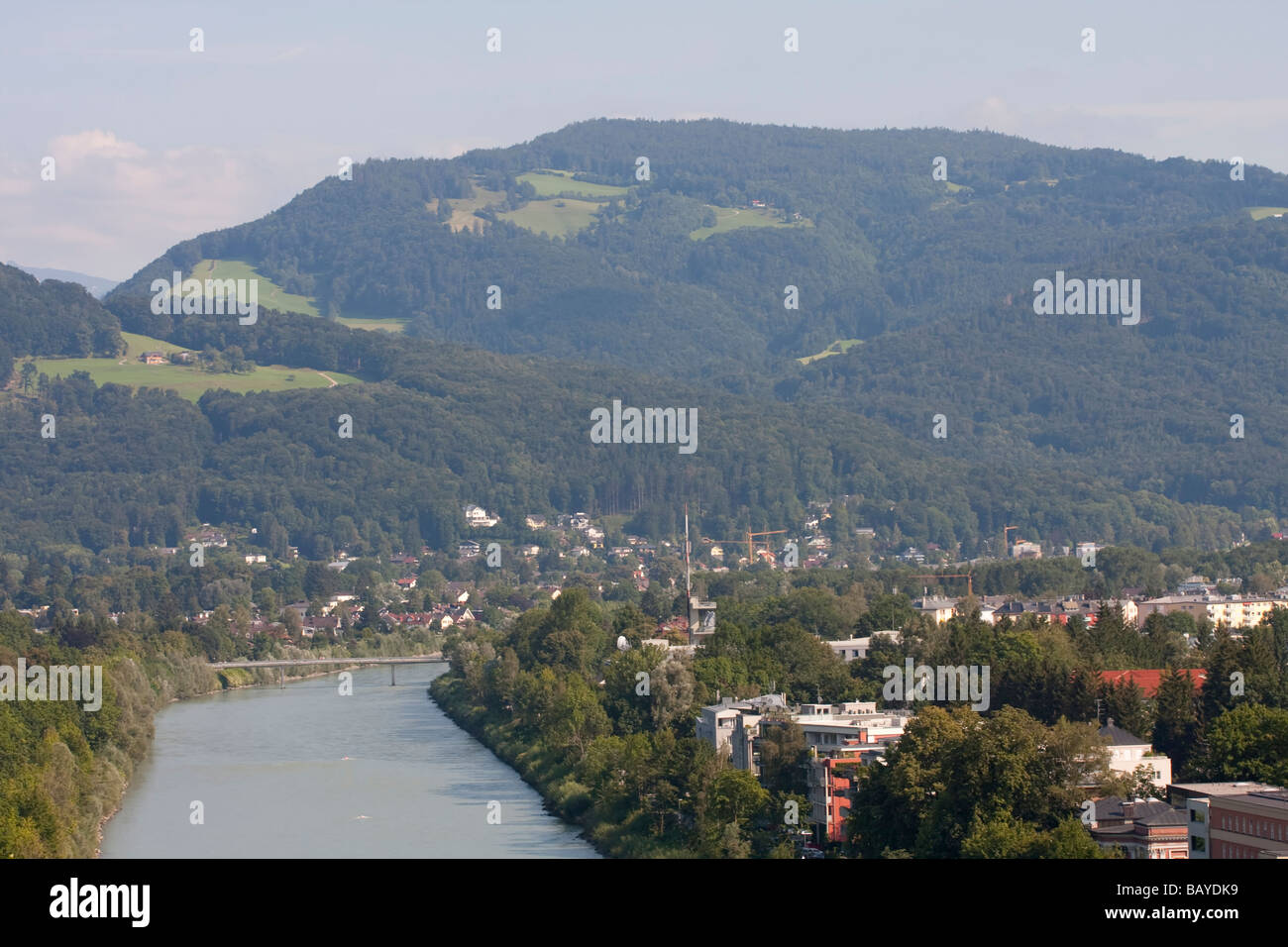 Una vista panoramica di Salisburgo con un fiume che scorre, edifici residenziali, foreste verdi e colline ondulate sotto un cielo azzurro. Foto Stock
