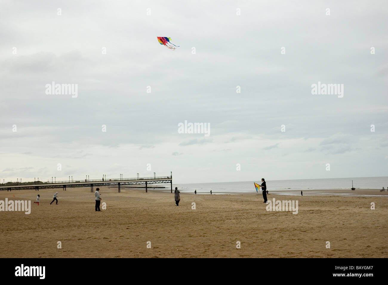 La gente volare un aquilone in un freddo bank holiday a Skegness Beach Foto Stock