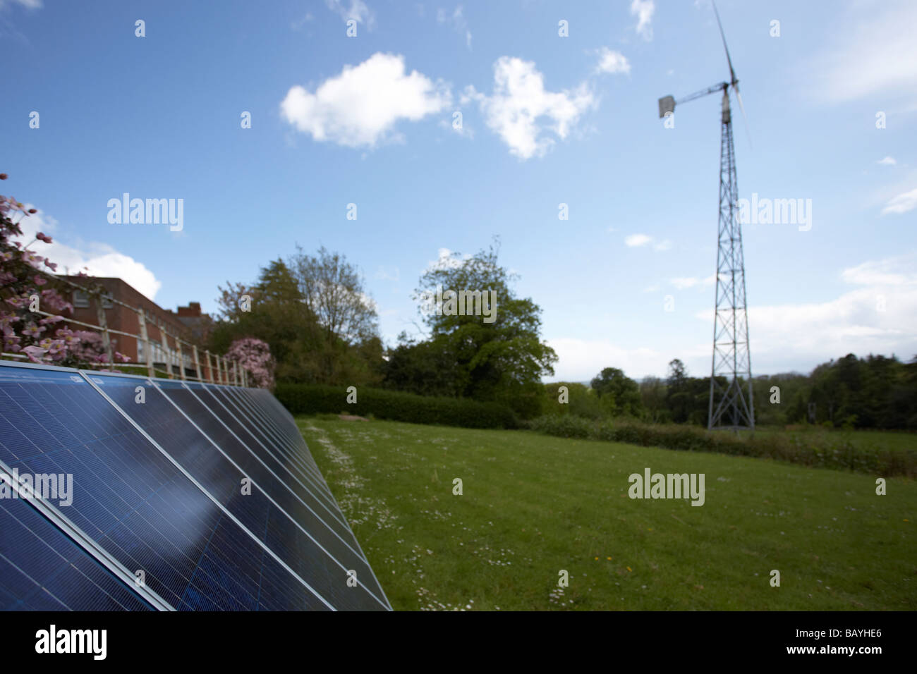 Sole che splende in giù su un array di tinta blu fotovoltaico in silicio policristallino pannelli solari e medie turbine eoliche Foto Stock