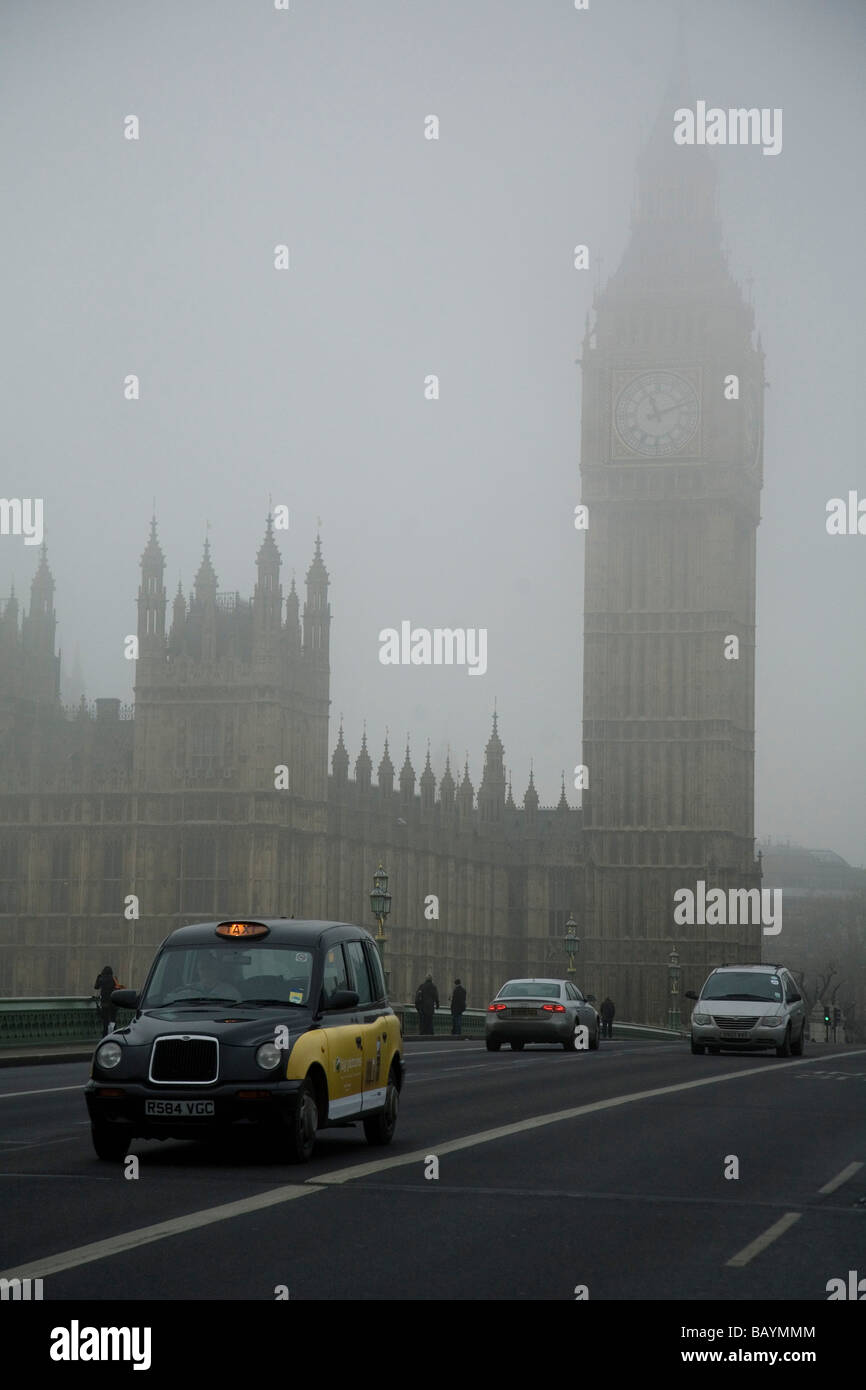 Il Big Ben e Westminster Bridge in una fitta nebbia su un gennaio giornata invernale e. Un taxi nero sta attraversando il ponte. Foto Stock