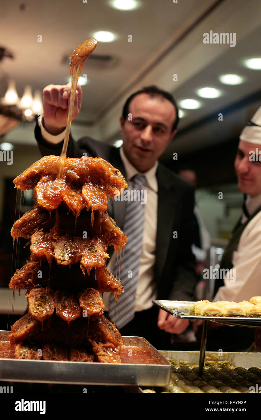 Cameriere versando lo sciroppo di zucchero su un display il baklava in un ristorante di Istanbul finestra Foto Stock