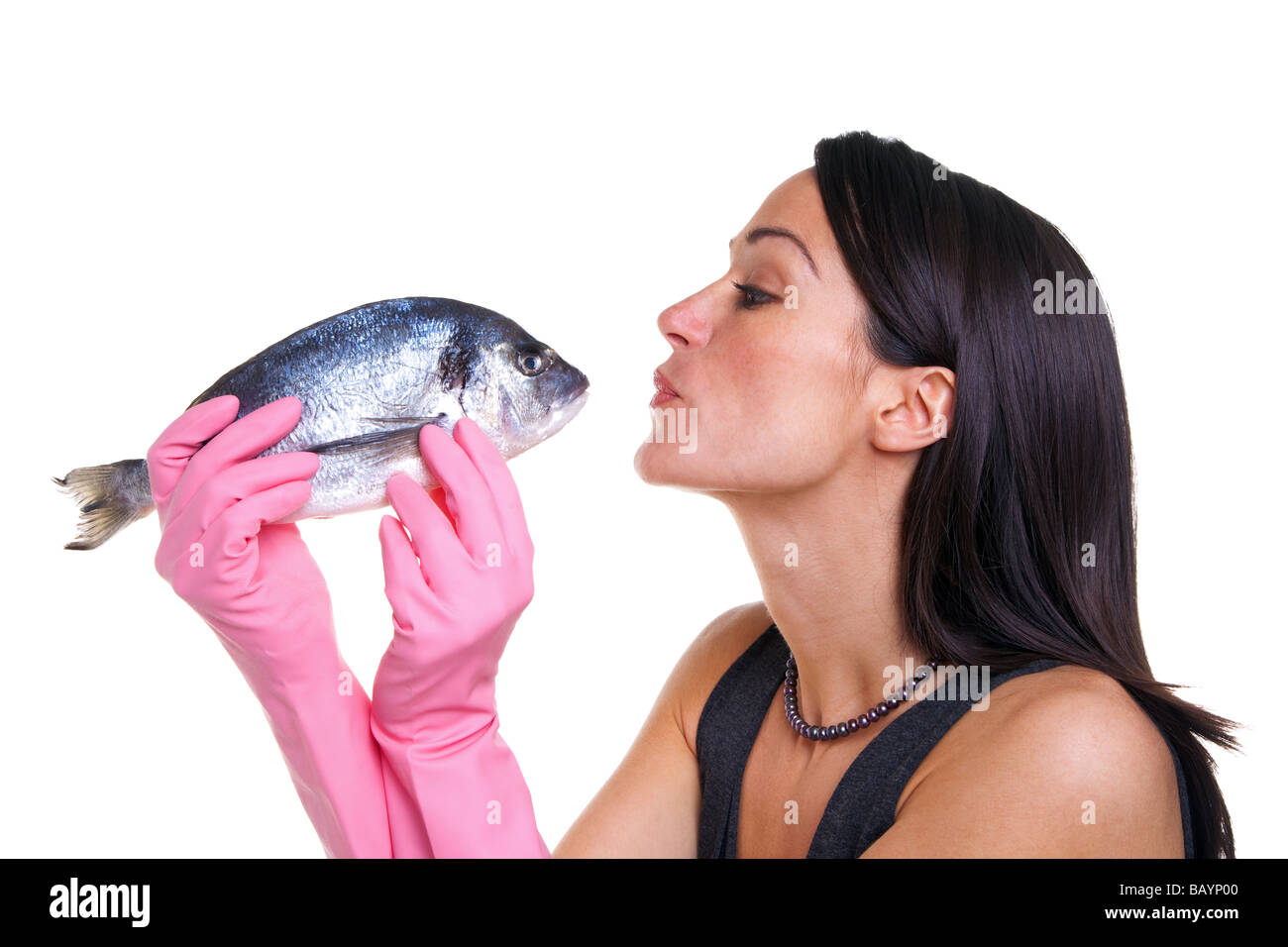 La donna in rosa di guanti di gomma attorno a baciare un pesce isolato su sfondo bianco Foto Stock